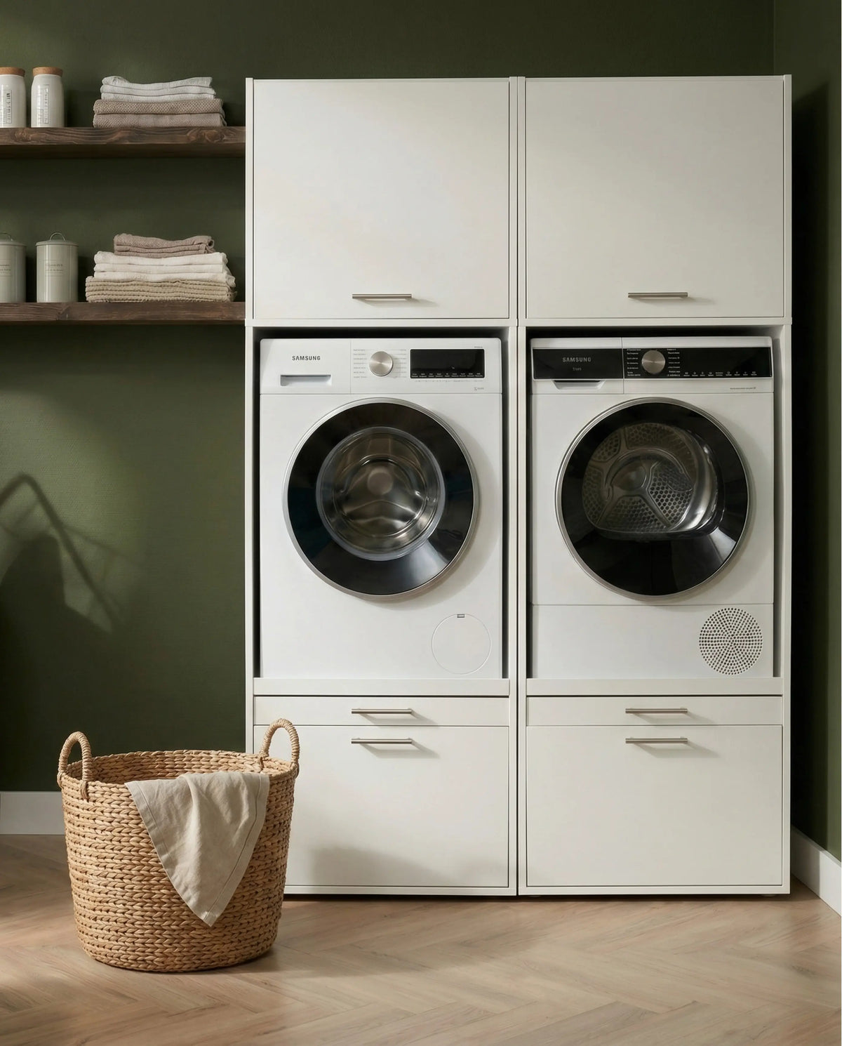 White front-load washer and dryer set stacked inside matching tall cabinetry with drawers, against a green wall.