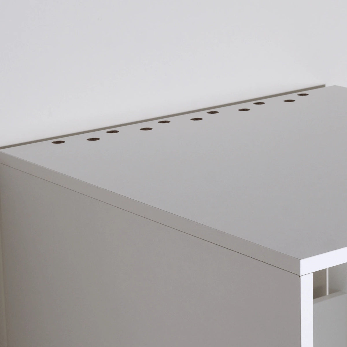 Metal drawer slide rail and white wooden cabinet corner with mounting bolt on wood floor background.
