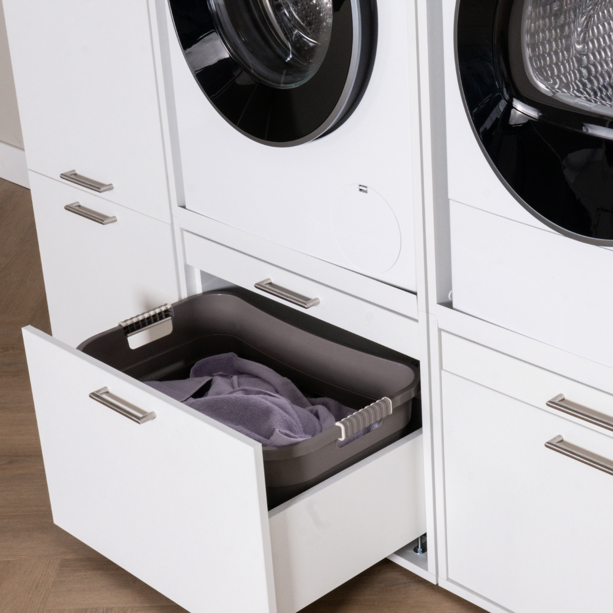 Built-in white cabinet drawer open with a gray laundry basket holding folded clothes inside.