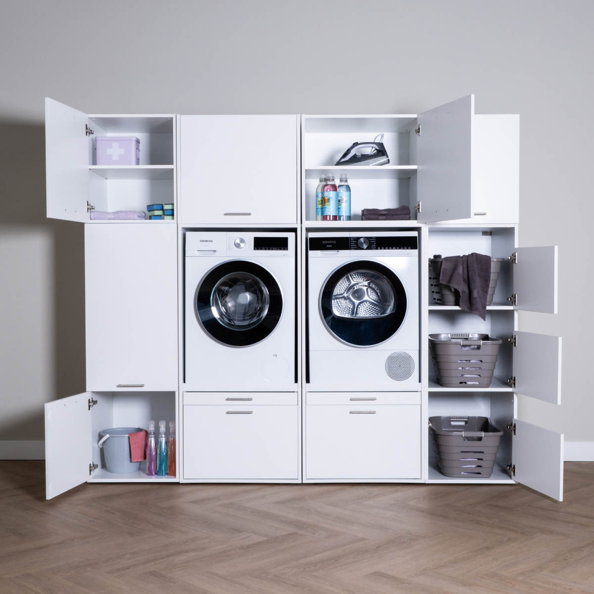White modular laundry storage unit with open cabinets, front-load washer and dryer, folded towels, and laundry baskets.